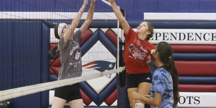 (Brad Davis/For LootPress) Independence's Jaina Davis, middle, taps the ball across as teammate Aubrey Cantrell tries to block during practice August 18 in Coal City.