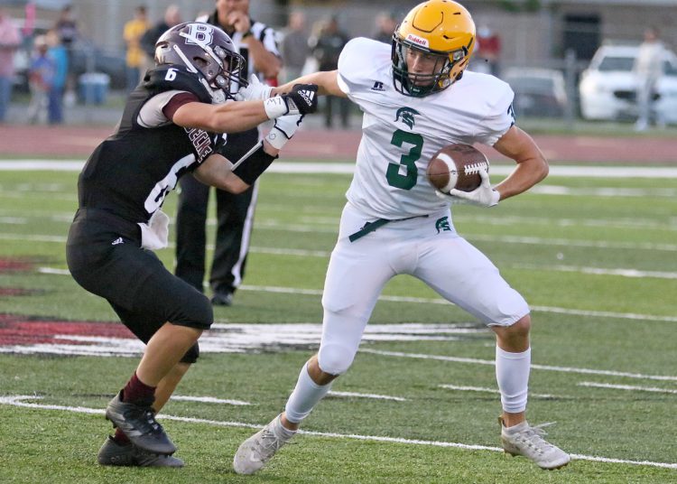 (Brad Davis/For LootPress) Greenbrier East's Bryson Ormsbee stiff-arms Woodrow Wilson defender Bradley Snyder to break loose for a touchdown on the Spartans' first offensive play of the game Friday night in Beckley.