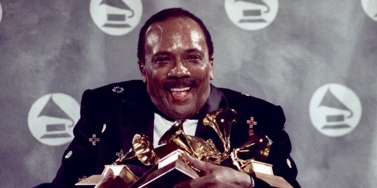 Quincy Jones cradles his Grammy awards including 7 album of the year awards, for his eclectic album "Back on the Block" during the 33rd annual Grammy Awards, at New York's Radio City Music Hall the night of Feb.20,1991. Quincy Jones died at age 91. (AP Photo/Susan Ragan, File)