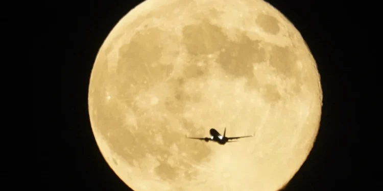 An airplane flies past the moon as it rises over Lake Michigan, Thursday, Oct.
17,2024, in Chicago. (AP Photo/Kiichiro Sato)